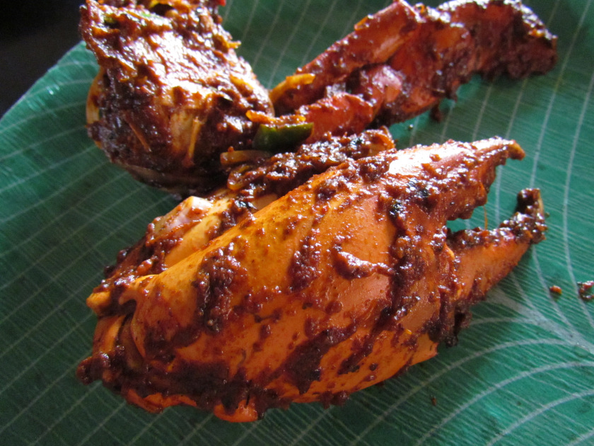 Cooked crab in a richly coloured sauce, served on a green leaf.