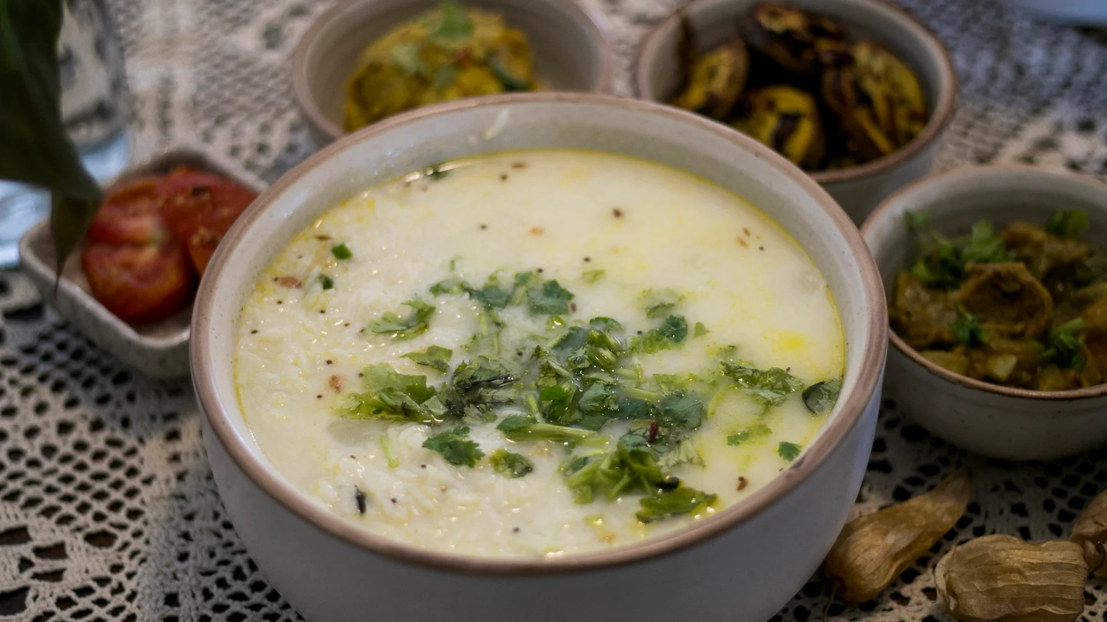 Pakhala at the centre of a meal, with a red tomato accompaniment partly visible on the left.