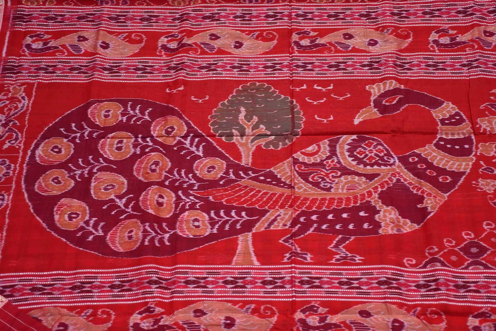 Peacock figures and floral patterns across a red Sambalpuri sari pallu